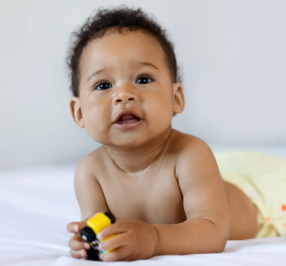 Bebê de barriga para baixo explorando um brinquedo